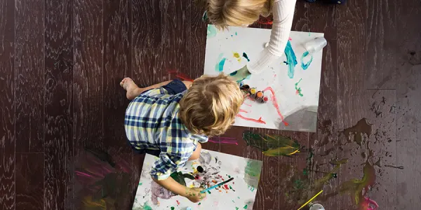 Boy sitting on hardwood making a mess painting