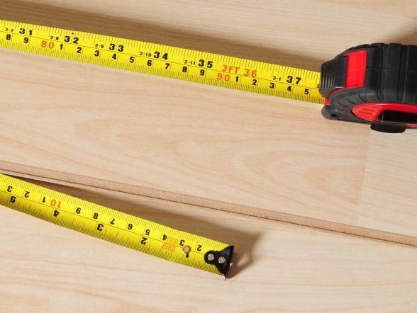 A measuring tape on top of wooden floor planks